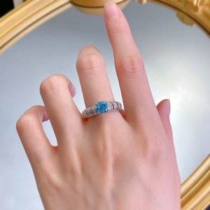Detailed macro shot of blue cushion cut gemstone ring with spiral diamond pavé band