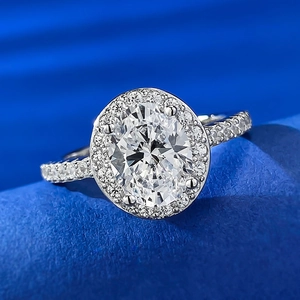 Macro shot of oval-cut halo ring with side diamonds on elegant dark blue velvet