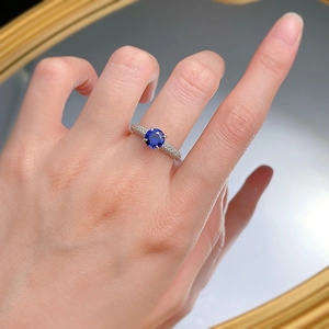 Detailed view of an S925 silver ring featuring a blue sapphire and diamond halo on a finger