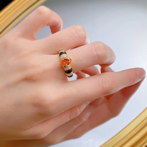 Détail d'une bague en argent S925 avec pierre orange et anneau doré émaillé noir