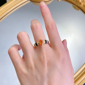 Détail d'une bague vintage plaquée or avec pierre orange ovale et émail noir