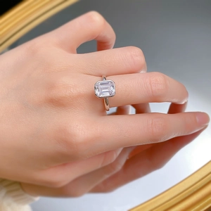Détail d'une bague avec pierre taille émeraude et anneau argenté sur la main