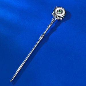 Macro shot of silver bamboo-style hair pin with green chalcedony gemstone on blue surface