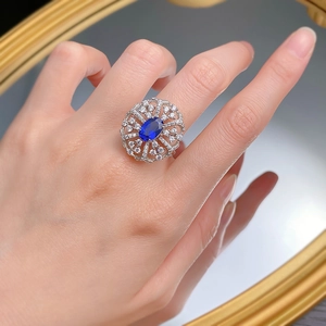 Mirror reflection showing a hand wearing a grand royal blue sapphire ring with halo design