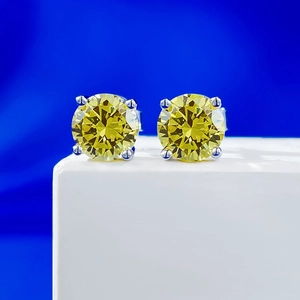 Detailed macro shot of yellow round cut moissanite earrings with four-prong silver setting