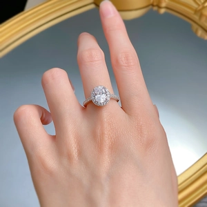 Detail of a 925 silver halo ring with oval-cut stone on a mirror surface