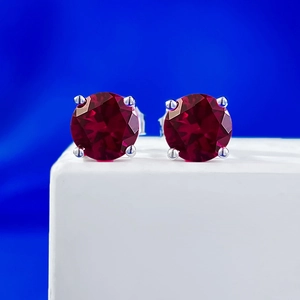 Macro shot of 1 carat round red zircon earrings with classic 4-prong silver setting