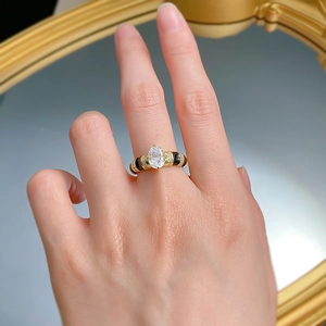 Macro view of oval white zircon ring with black enamel and gold-plated silver band