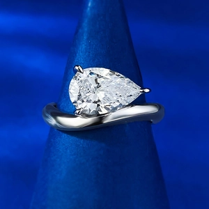 Macro shot of 2 carat pear cut diamond ring with S925 silver wave band and 3-prong setting