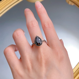 Macro view of pear cut black zircon ring with pave stones on silver metal band