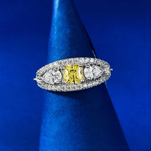Three-stone ring with cushion-cut yellow stone and pear-shaped side accents on blue display
