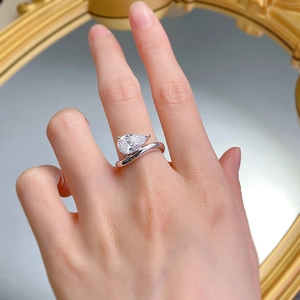 Close-up of a pear-shaped teardrop gemstone ring with a curved silver band on hand