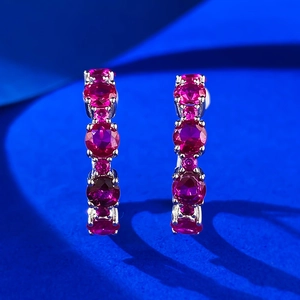 Macro shot of S925 sterling silver earrings with inlaid pink crystals on blue background