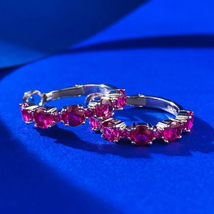 Macro shot of S925 silver hoop earrings featuring five vibrant red round gemstones