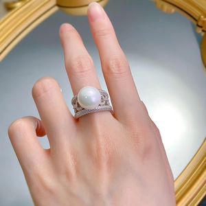 Detailed close-up of a 12mm shell pearl ring with micro-pave silver setting on finger