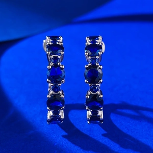 Detailed view of silver hoop earrings featuring pavé-set dark blue round gemstones