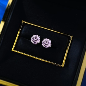 Macro view of pink round cut moissanite stud earrings in a classic four-prong silver setting