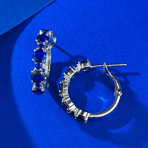 Detail of luxury S925 sterling silver hoop earrings set with round blue sapphire stones