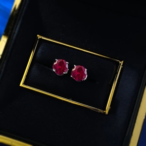 Macro shot of 1ct red round-cut stud earrings in classic four-prong silver setting