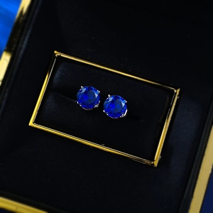 Macro shot of 6.5mm round cut deep blue sapphire stud earrings in classic four-prong setting