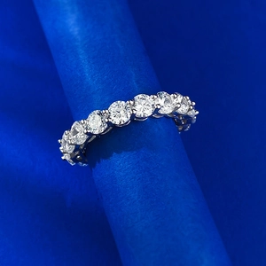 Macro shot of a 925 sterling silver eternity ring with prong-set diamonds on a blue stand
