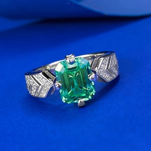 Macro view of emerald cut green gemstone ring with geometric pave diamond detailing