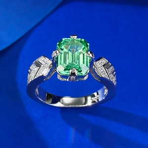 Detailed macro view of an emerald cut green gemstone ring with side pave diamonds