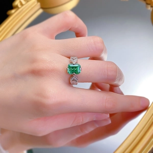 Macro shot of 925 silver ring with emerald-cut green gemstone and V-shaped diamond accents