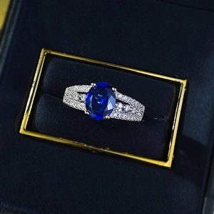 Macro shot of silver ring with oval blue gemstone and white diamonds in a luxury box