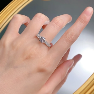 Close-up of S925 silver engagement ring featuring a round moissanite on a model's finger