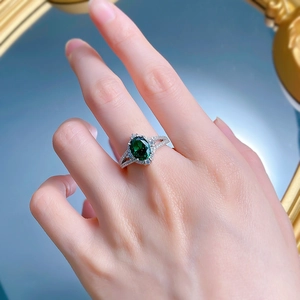 Detail of S925 silver ring featuring an emerald-cut green stone with side diamonds