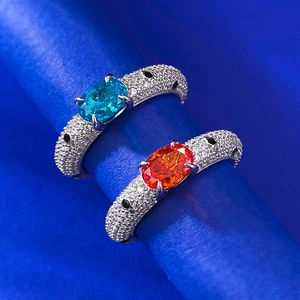 Macro detail of jaguar style rings with oval orange and teal stones in pavé diamonds