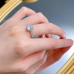 Close-up of S925 sterling silver halo ring with oval cut white diamond on model hand