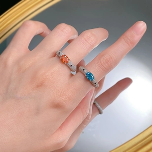 Macro detail of silver rings featuring orange and blue gemstones with pavé zircon setting