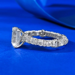 Detail of emerald cut gemstone ring with full pavé diamonds on a blue silk surface