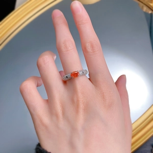 Macro shot of 925 silver ring featuring an oval orange gemstone and pavé diamonds