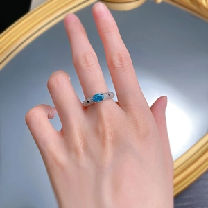 Macro shot of a S925 silver ring featuring a blue Paraiba stone and pavé set diamonds