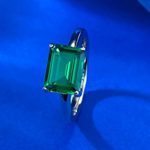 Macro side view of emerald cut green gemstone set in silver four-prong mounting ring