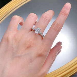 Elegant S925 sterling silver ring with emerald cut diamond on model hand with golden mirror