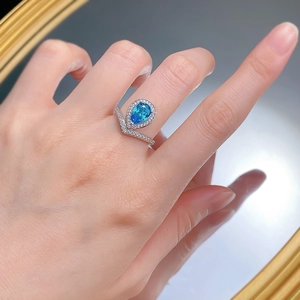 Macro shot of S925 silver ring featuring a pear-cut blue gemstone and V-shaped band