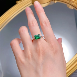 Detailed view of rectangular emerald cut green gemstone ring with silver four-prong setting