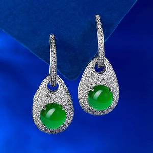 Detail of green jade drop earrings with micro-set diamonds on a blue velvet stand