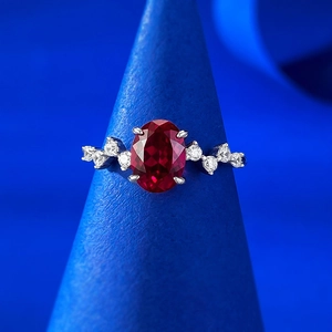 Gros plan d'une bague en corindon rouge sang de pigeon ovale sur support bleu