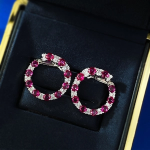 Détail de boucles d'oreilles rondes en argent S925 avec rubis rouge et halo de diamants