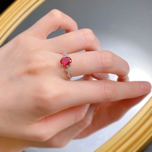 Gros plan d'une bague rubis ovale portée avec anneau en argent S925 et zirconias