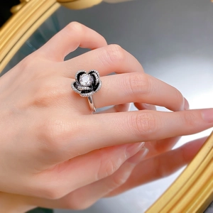 Macro shot of S925 silver camellia ring with sparkling round white crystals on a hand