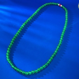 Collana di perle in calcedonio verde con ciondolo in argento su sfondo blu navy materico