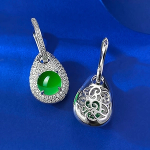 Macro detail of silver drop earrings with green gemstone and intricate hollow carving
