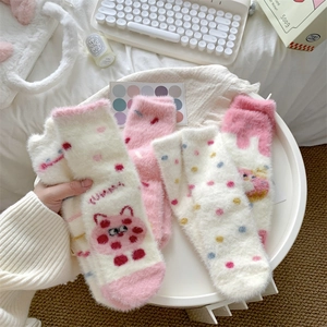 Close-up of thick pink coral fleece socks with polka dots and cartoon donut patterns
