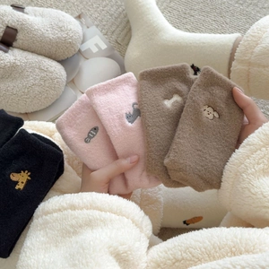 Detail view of colorful warm fleece socks with cute animal embroidery on soft material